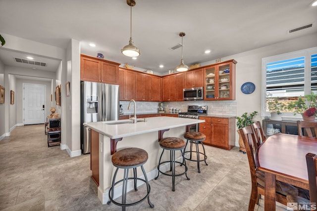 kitchen featuring stainless steel appliances, brown cabinets, visible vents, and a sink