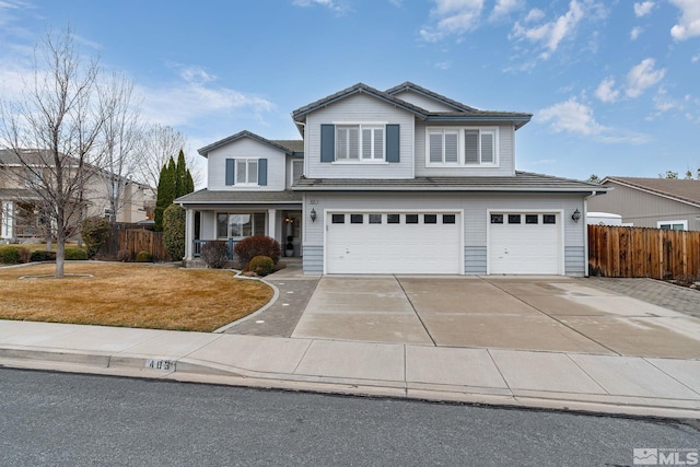 traditional home featuring a garage, concrete driveway, covered porch, and fence