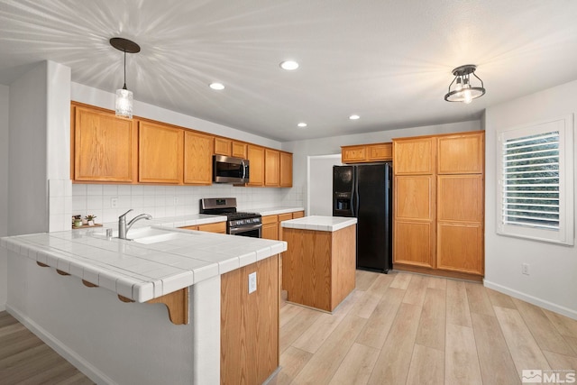 kitchen with a sink, stainless steel appliances, a peninsula, and backsplash