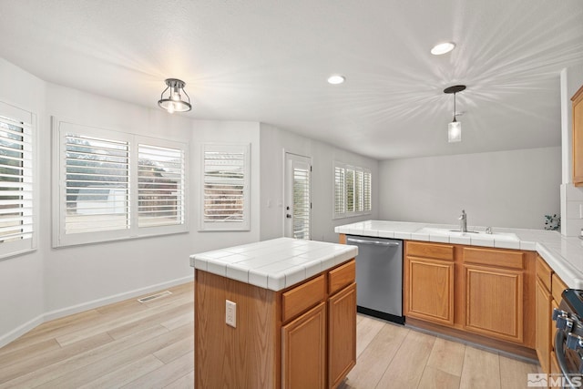 kitchen featuring stainless steel appliances, a sink, decorative light fixtures, and light wood-style floors