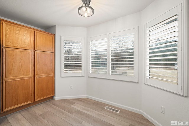 interior space with visible vents, light wood-style flooring, baseboards, and multiple windows