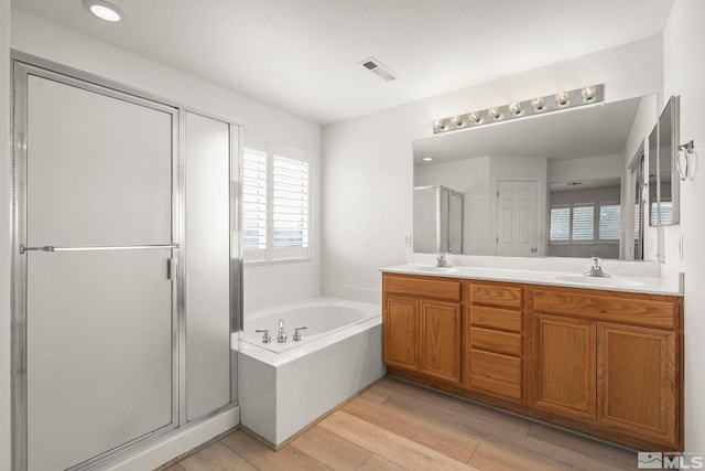 full bath featuring a garden tub, visible vents, a stall shower, a sink, and wood finished floors