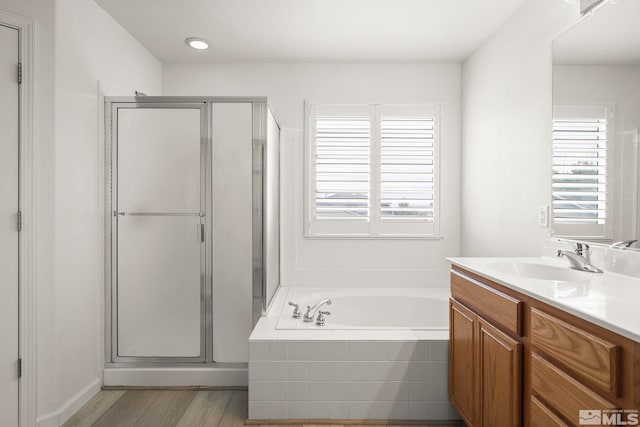 full bathroom with a garden tub, vanity, a shower stall, and wood finished floors