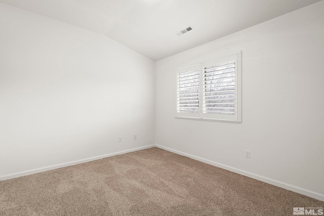 empty room featuring vaulted ceiling, carpet flooring, visible vents, and baseboards