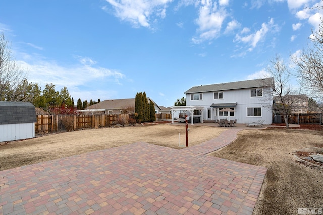 rear view of property featuring a patio area, a fenced backyard, an outdoor structure, and a pergola