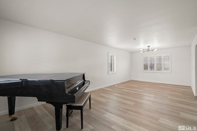 living area with light wood-style flooring, baseboards, and a notable chandelier