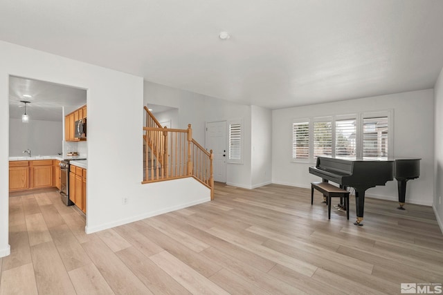 sitting room featuring light wood-style flooring, baseboards, and stairs