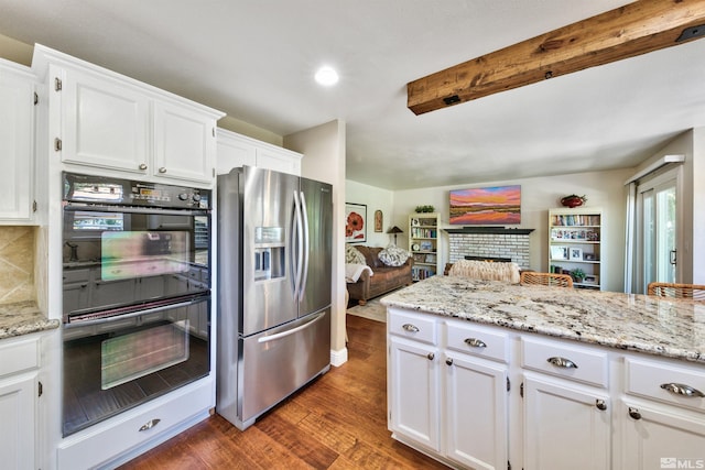 kitchen featuring dobule oven black, decorative backsplash, dark wood-style flooring, white cabinetry, and stainless steel refrigerator with ice dispenser