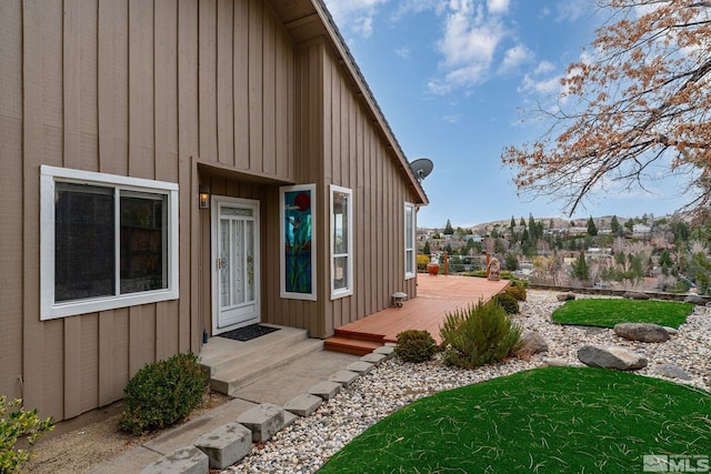 view of exterior entry with a wooden deck and board and batten siding