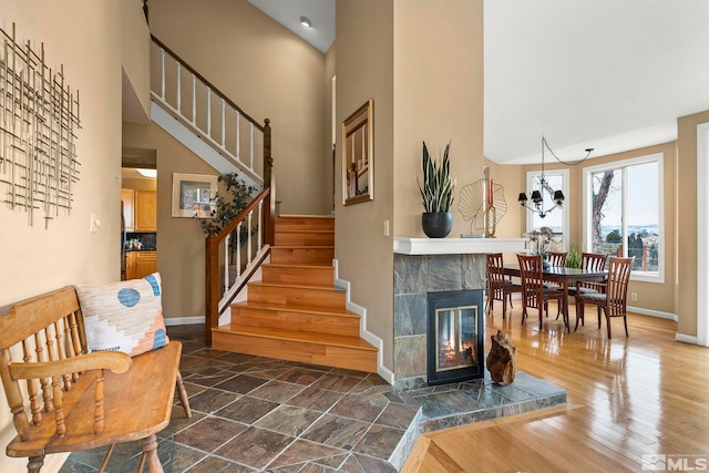 staircase featuring wood finished floors, baseboards, a towering ceiling, and a tile fireplace