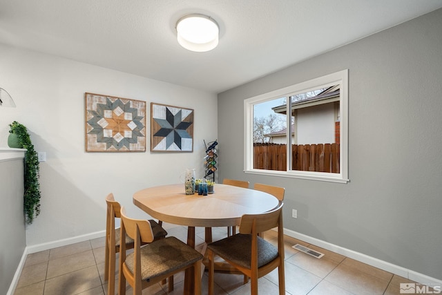 dining space featuring baseboards, visible vents, and light tile patterned flooring