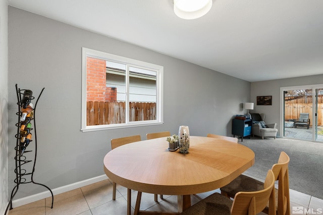 dining area with light carpet, plenty of natural light, baseboards, and light tile patterned floors