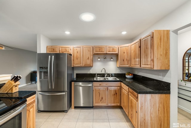 kitchen with stainless steel appliances, dark countertops, light tile patterned flooring, and a sink