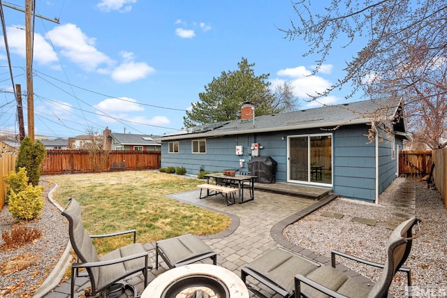 back of property featuring a fenced backyard, a chimney, a patio, and a yard