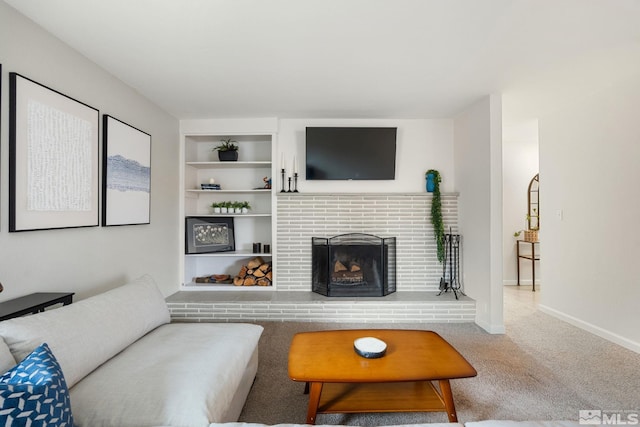 carpeted living room with a brick fireplace, baseboards, and built in features