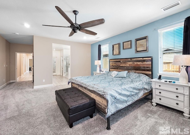 bedroom featuring a ceiling fan, light colored carpet, visible vents, and baseboards