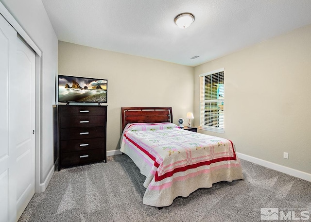 carpeted bedroom with a closet, visible vents, and baseboards