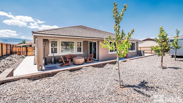 back of house featuring a tile roof, a patio, stucco siding, an outdoor fire pit, and a fenced backyard