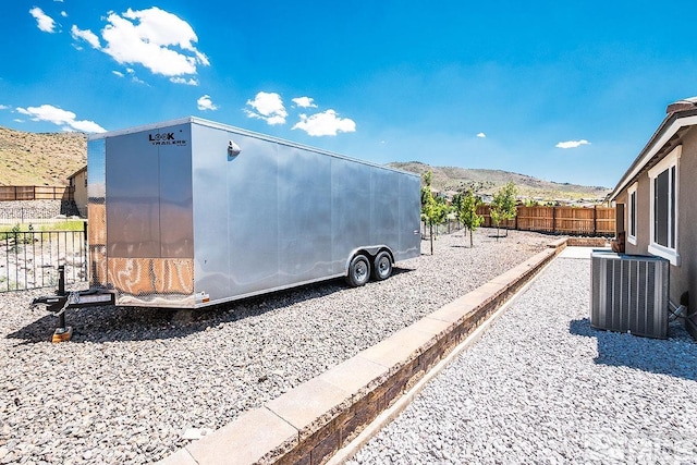 exterior space with fence, a mountain view, and central AC