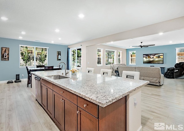 kitchen featuring light stone countertops, light wood-style floors, open floor plan, and a sink