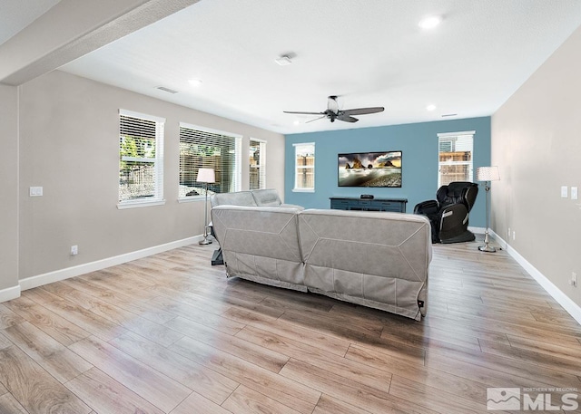 living room featuring light wood-type flooring, a healthy amount of sunlight, baseboards, and a ceiling fan