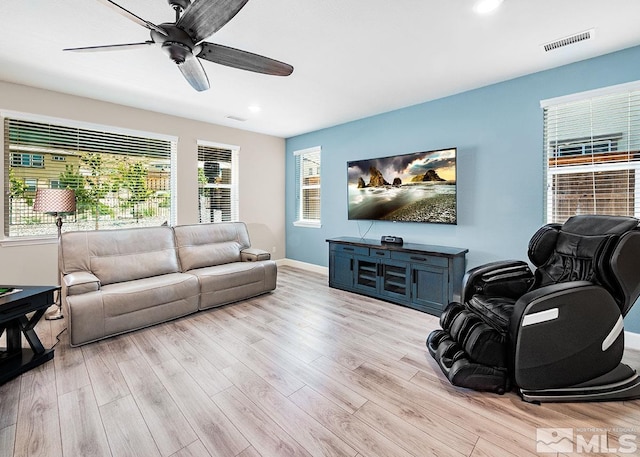 living room with baseboards, a ceiling fan, visible vents, and light wood-style floors