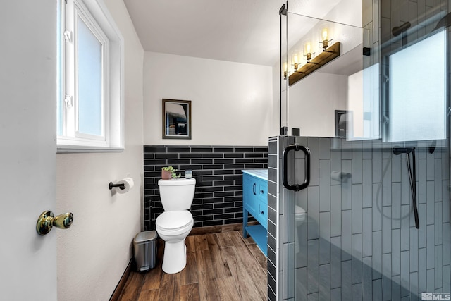 bathroom with a stall shower, tile walls, toilet, and wood finished floors