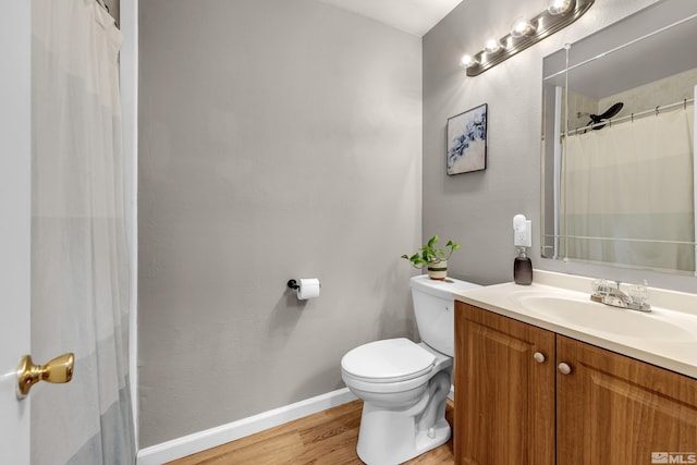 bathroom featuring baseboards, a shower with shower curtain, toilet, wood finished floors, and vanity