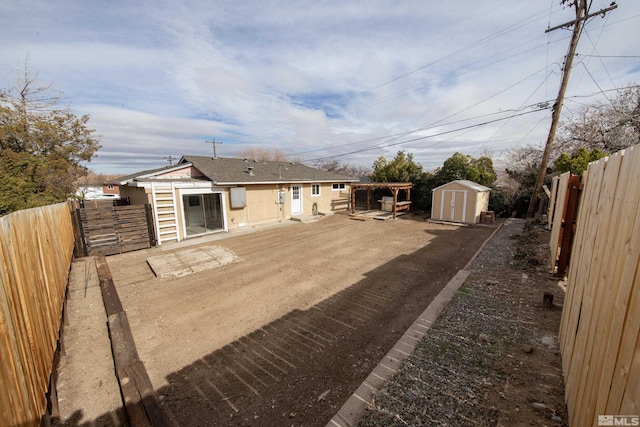 exterior space with an outbuilding, roof with shingles, a patio, a storage unit, and a fenced backyard