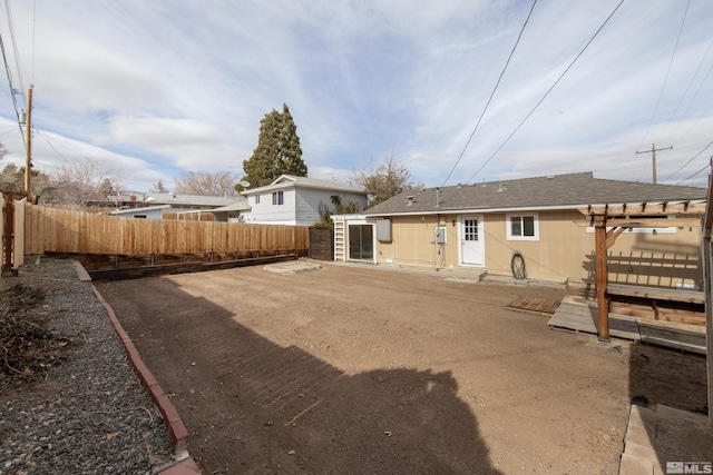 rear view of property featuring entry steps, fence private yard, and roof with shingles