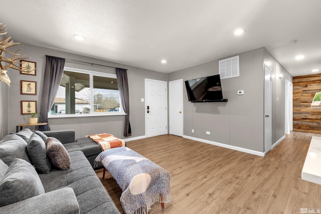 living room featuring baseboards, recessed lighting, visible vents, and light wood-style floors