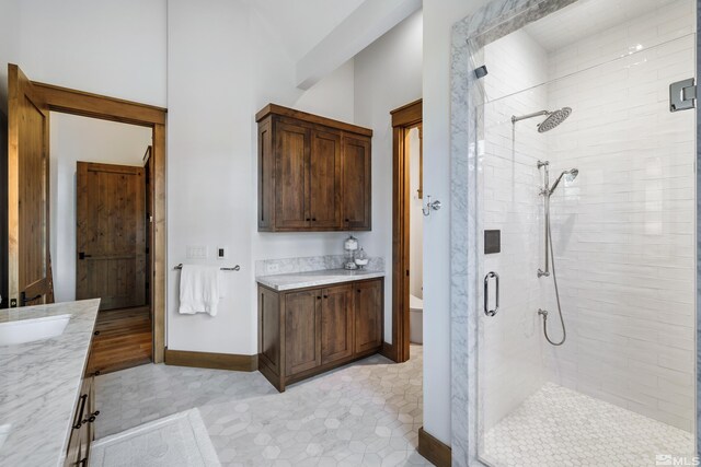 full bath featuring a stall shower, vanity, and baseboards