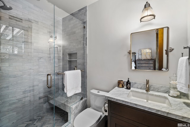 bathroom with toilet, a shower stall, and vanity