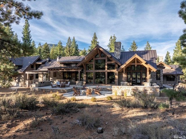 back of property featuring a standing seam roof, a patio area, a chimney, and metal roof