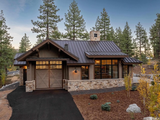 view of front of house featuring metal roof, aphalt driveway, a standing seam roof, and stone siding