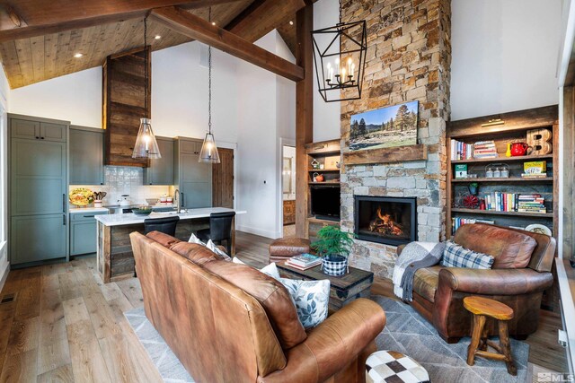 living area with a stone fireplace, light wood finished floors, beamed ceiling, and wood ceiling