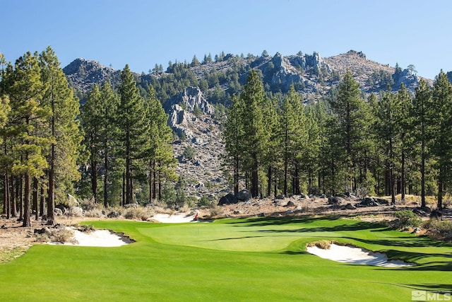 view of home's community with a yard, a mountain view, and golf course view