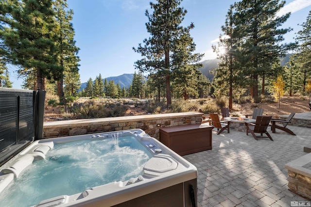 view of patio / terrace featuring an outdoor fire pit, a mountain view, and a hot tub