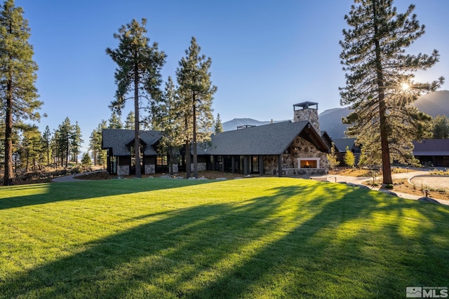 rear view of property with stone siding and a lawn