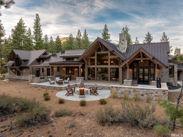 rear view of house featuring metal roof, a patio, french doors, a standing seam roof, and an outdoor living space with a fire pit