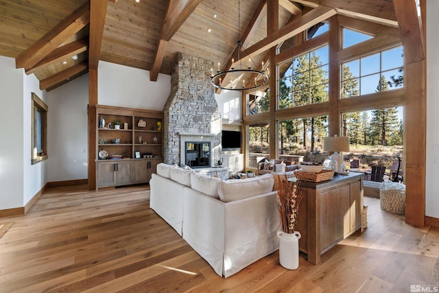 living room with baseboards, wood ceiling, an inviting chandelier, a stone fireplace, and light wood-type flooring