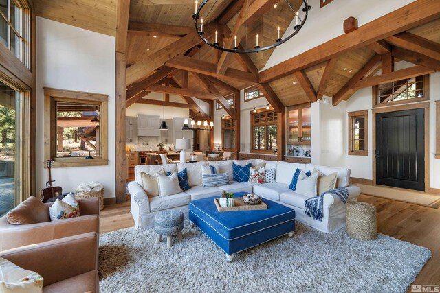 living room with baseboards, wood finished floors, a notable chandelier, high vaulted ceiling, and beam ceiling