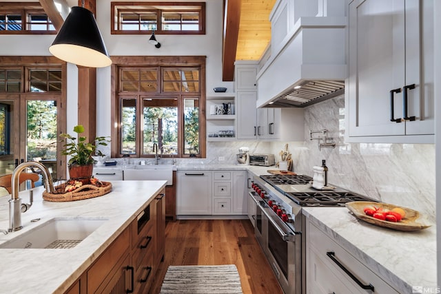 kitchen with decorative backsplash, custom exhaust hood, a sink, and double oven range