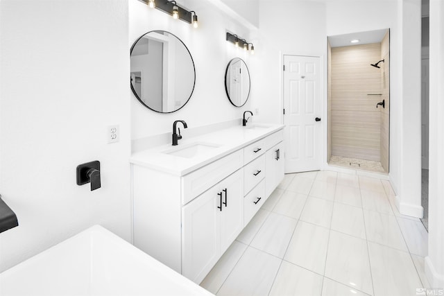 full bathroom featuring double vanity, a tile shower, a sink, and tile patterned floors