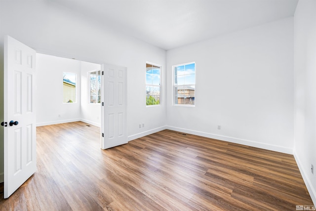 spare room with baseboards and wood finished floors