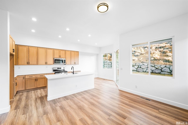 kitchen featuring stainless steel appliances, light countertops, visible vents, light wood-style floors, and a sink