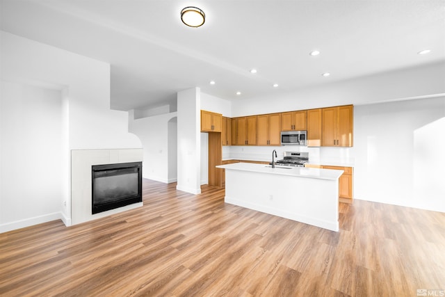 kitchen featuring an island with sink, light wood-style flooring, appliances with stainless steel finishes, light countertops, and a sink