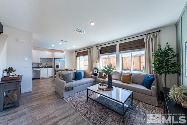 living room with recessed lighting, baseboards, visible vents, and light wood finished floors