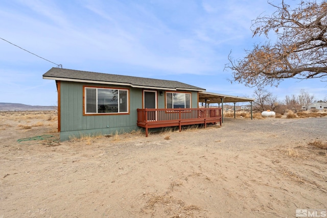 view of front of property with a carport, a shingled roof, and a wooden deck