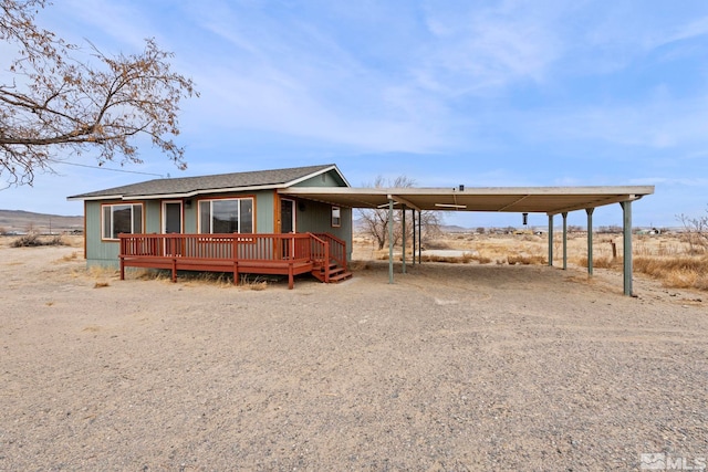 view of front of home featuring driveway, a shingled roof, and an attached carport